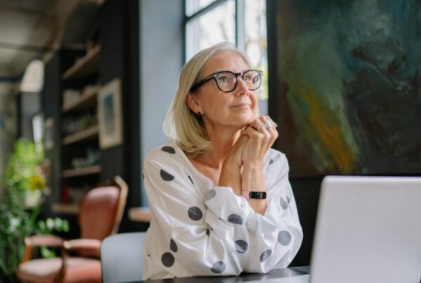 A woman at a desk in front of computer looking hopeful