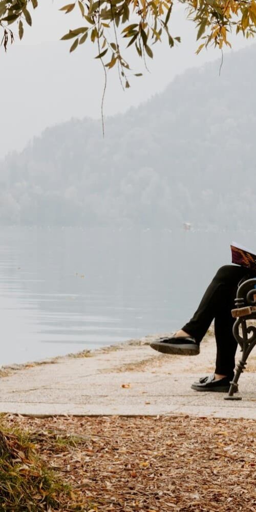Woman reading on a bench near water
