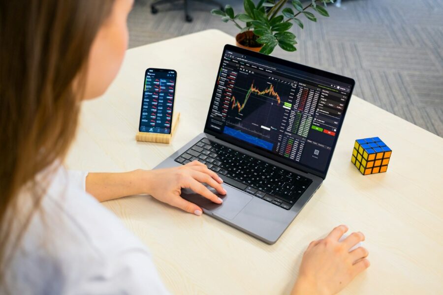Person at computer with stock market trends