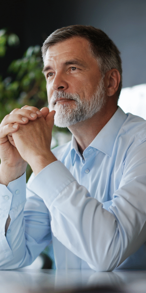 Late-career business owner pensively thinking in office